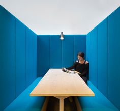 a woman sitting at a table in a room with blue booths on the walls and floor