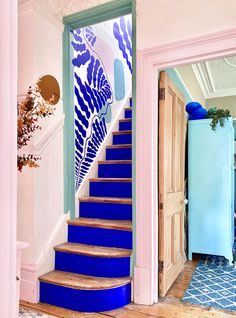 a blue and white staircase leading up to a pink room with an aqua refrigerator in the background