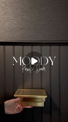 a person is holding a tray in front of a wall with the words moody powder room on it