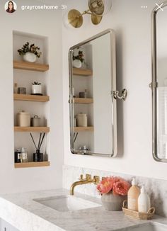 a bathroom sink with two mirrors above it and shelves on the wall next to it