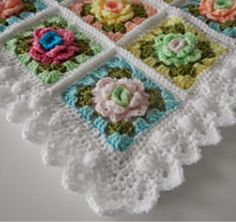 there is a crocheted tablecloth with flowers on it and four squares in the middle