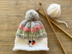 a knitted hat and two knitting needles on a table