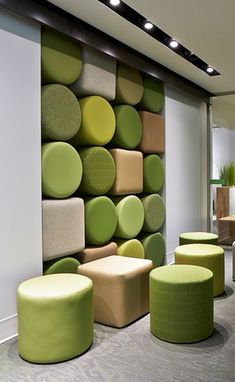 an office with green and yellow furniture in front of a large wall made out of circles