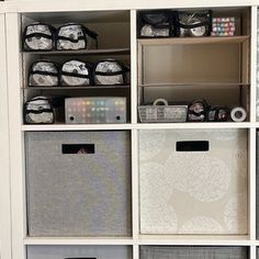 a white bookcase filled with lots of boxes and bins next to a wall