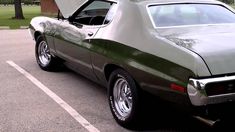 a green muscle car parked in a parking lot