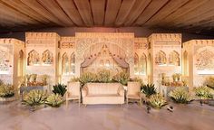 a stage set up for a wedding with chairs and flowers on the floor in front of it