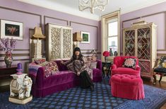 a woman sitting on top of a purple couch in a living room filled with furniture