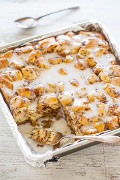 a casserole dish with cinnamon rolls and cream sauce on top, ready to be eaten