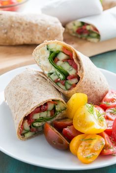 there is a wrap on the plate with tomatoes and cucumbers