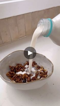 a bowl filled with cereal and milk being poured into it