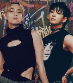 two young women standing next to each other in front of graffiti covered wall with their arms crossed