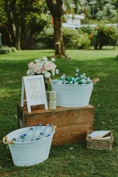 three buckets with flowers are sitting in the grass near a sign and other items