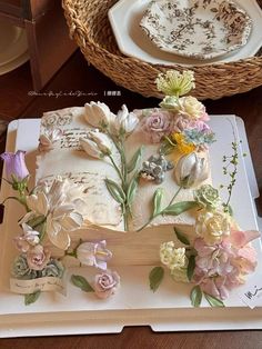 a cake decorated with flowers on top of a white tray next to a wicker basket