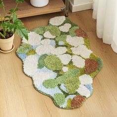 a green and white rug on the floor next to a potted plant