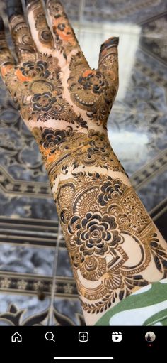 a person's hand with henna tattoos on their arm and hands, in front of a mirror