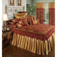 a bed with red and gold bedspread in a bedroom next to a window