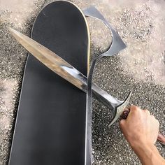 a person is holding a large knife in front of a pair of black flip flops