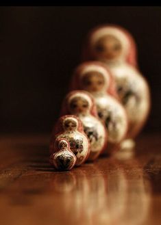 there are many small dolls sitting on the table together, all lined up in a row