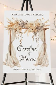 a welcome sign for a wedding with flowers and draperies on the front, hanging from an easel