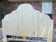 a wooden headboard sitting on top of a metal bench next to a brick building