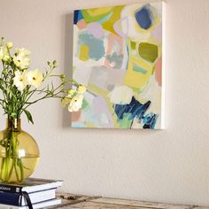 a vase filled with white flowers sitting on top of a wooden table next to a painting