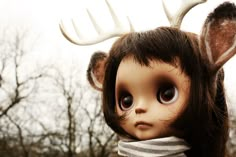 a close up of a doll with antlers on its head and scarf around it's neck