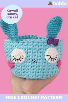 a hand holding a small blue crocheted bag with ears and eyes on it