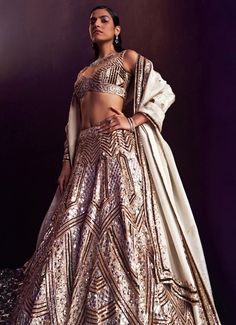 Introducing the stunning Gold Sequins Embroidered Bridal Lehenga Set is an exquisite blend of traditional elegance and modern sophistication. Crafted from luxurious tissue fabric, this gold lehenga showcases meticulous craftsmanship with its rich embellishments of gold and antique sequins, crystals, and bugle beads. The voluminous lehenga skirt flows effortlessly, exuding grace and grandeur. Paired with a matching embellished blouse offers a flattering, tailored fit. Completed with a delicate dupatta that drapes elegantly over the shoulders, adding a touch of ethereal charm. Perfect for the bride or bride-to-be, this lehenga set is designed to make you dazzle on your special day, ensuring every moment is captured in timeless beauty. Composition : Lehenga, Blouse and Dupatta - Tissue Care: Reception Sets With Intricate Embroidery, Fitted Wedding Sets With Mirror Work, Fitted Kundan Gown With Intricate Embroidery, Fitted Wedding Choli With Mirror Work, Semi-stitched Choli For Reception, Traditional Drape, Traditional Drape Wedding Sets With Mirror Work, Fitted Lehenga With Mirror Work For Wedding, Transitional Gold Lehenga With Mirror Work, Traditional Sets With Mirror Work For Reception