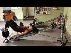 a woman laying on top of a rowing machine in a room with other exercise equipment