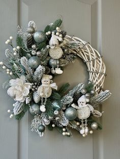 a christmas wreath on the front door with ornaments and teddy bears hanging from it's sides