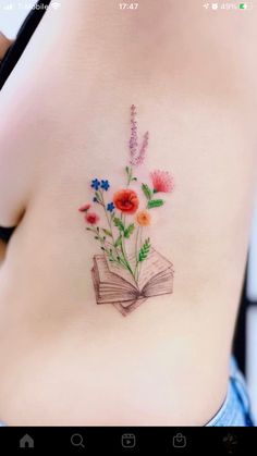 an open book and flowers tattoo on the stomach