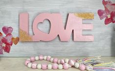 the word love is spelled with pink and gold letters on a white table next to some candy