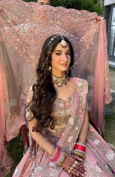 a woman in a pink bridal outfit sitting on the ground next to a sheer curtain