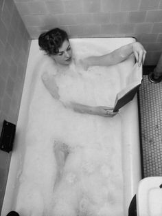 a woman in a bathtub reading a book