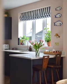 a kitchen with two stools and a window in the back ground, next to an island