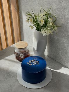 a blue cake sitting on top of a table next to a vase filled with flowers