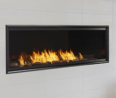 a modern fireplace with fire flames in the middle and white tiles on the wall behind it