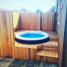 an inflatable hot tub sitting on top of a wooden deck next to steps