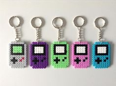 four pixel keychains with different colors and designs on them, each featuring a gameboy