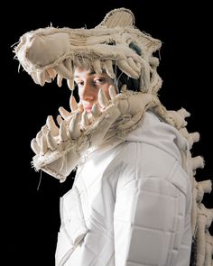 a woman in white is wearing a large animal's head and claws on her face