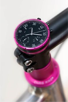 a pink and black clock sitting on top of a pipe