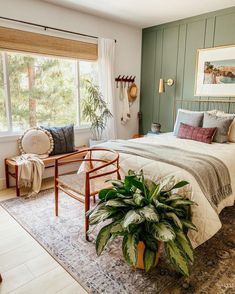 a bedroom with a bed, chair and potted plant