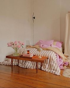 a room with a bed, table and flowers on the floor in front of it