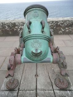 an old green fire hydrant sitting on top of a wooden bench next to the ocean