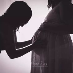 a pregnant woman is standing next to her belly while holding the hand of another pregnant woman