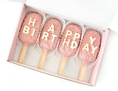 four pink lollipops with the words happy birthday on them in a box