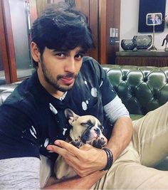 a man sitting on a couch holding a small dog