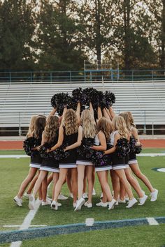 a group of cheerleaders huddle together on the field