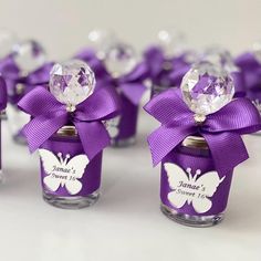 small glass jars with purple bows and crystal balls in them, each decorated with a butterfly