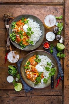 two plates filled with rice and chicken next to drinks on a wooden table, top view from above